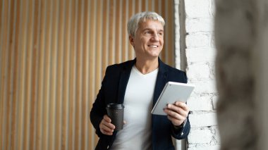 İnternette gülümseyen bir sitede çalışıyor. Adam, ofisteki beyaz saçlı, şık ve serbest çalışan biri..