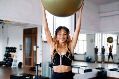 Koç afro görünüm egzersizleri kardiyo sisteminde aktif. Güçlü bir atletik kadın, parlak bir spor salonunda tek başına antrenman yapar. Sağlıklı bir yaşam tarzı ve dayanıklılık..