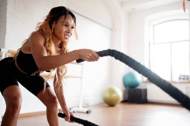 Kardiyo sistemi ve dayanıklılık için egzersiz. Spor için farklı ekipmanlarla kardiyo egzersizleri için fitness stüdyosu. Sportif ve sağlıklı bir yaşam tarzı. Güçlü bir kadın spor salonunda antrenman yapıyor..