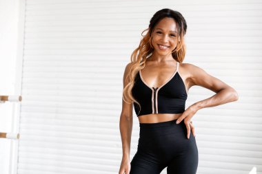 Güçlü bir atletik kadın, parlak bir spor salonunda tek başına antrenman yapar. Afro görünümlü gülümseyen bir antrenörün portresi kardiyo sisteminde aktiftir. Sağlıklı bir yaşam tarzı ve dayanıklılık..