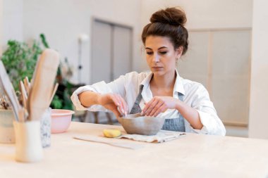 Bir heykeltıraş ve sofra takımı yapmak için bir atölye çalışması. Kadın el yapımı kil tabaklar yapmaya bayılıyor. Sinirleri yatıştırmak ve sakinleşmek için bir hobi. Seramik ustası bir ürün yapıyor..