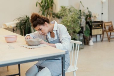 Seramik ustası stüdyo işyerinde profesyonel bir iş yapıyor. Bir kadının hobisi kille çalışmaktır. Üretim süreci. Heykeltıraş el yapımı sofra takımı yapar..