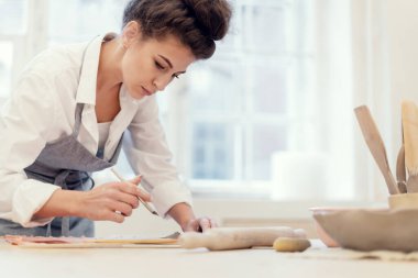 Seramik ustası stüdyo işyerinde profesyonel bir iş yapıyor. Bir kadının hobisi kille çalışmaktır. Heykeltıraş el yapımı sofra takımı yapar..