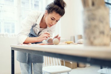 Bir kadının hobisi kille çalışmaktır. Heykeltıraş el yapımı sofra takımı yapar. Stüdyo işyerinde seramik uzmanı..