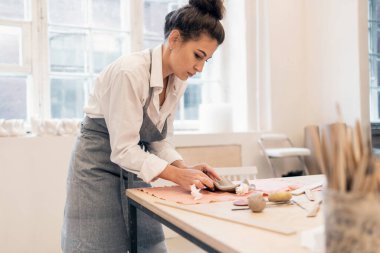 Bir kadının hobisi kille çalışmaktır. Heykeltıraş el yapımı sofra takımı yapar. Seramik ustası stüdyo işyerinde profesyonel bir iş yapıyor..