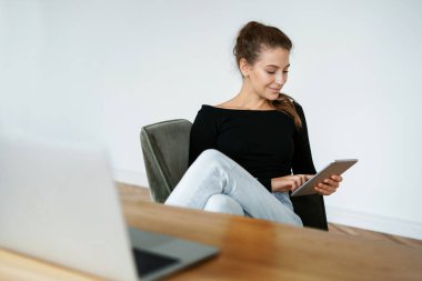 Tasarımcı internette bir aletle sörf yapıyor. Finansör müşterilerin e-postalarına cevap verir. Ev işyerinde serbest çalışan bir kadının portresi. Eş zamanlı çalışma müdürlüğü.