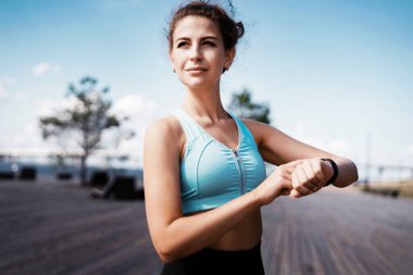 Sporcunun sağlıklı bir yaşam tarzı var. Kalori sayma koçu akıllı seke bakıyor. Kadınlar için spor ve giysi. Şehirde fitness molası. - Evet. Kilo vermek için kardiyo eğitimi.