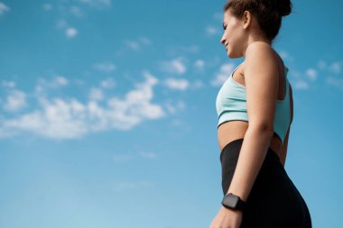 Sokakta spor yapan bir kadın. Fitness ve sağlıklı bir yaşam tarzı. Koç egzersizler arasında mola verir. Ellerdeki nabzı ölçmek için akıllı bir saat kullanıyor..