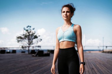 Antrenör akıllı bir saatin nabzını sayar. Kadınlar için spor ve giysi. Şehirde fitness molası. Kilo vermek için kardiyo eğitimi. Sporcunun sağlıklı bir yaşam tarzı var..