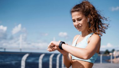 Kalori yakmayı ölçen akıllı modern kardiyo saati. Kendine güveni olan esmer bir kadının sağlıklı bir yaşam tarzı var. Atlet koşuya hazırlanıyor, vücudunu ısıtıyor..
