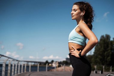 Vücut sağlığı atletizmi. Kardiyo sistemi eğitimi. Şehrin sokaklarında bir kadın mola veriyor. Koç rahat kıyafetlerle spor yapıyor..