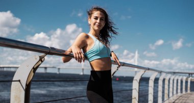 Kardiyo sistemi eğitimi. Şehrin sokaklarında bir kadın mola veriyor. Koç rahat kıyafetler içinde spor yapar. Vücut sağlığı atletizmi.