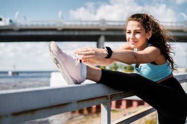 Şehirde spor yapıyor. Antrenör antrenmandan önce ısınma egzersizleri yapar. Sporcunun sağlıklı bir yaşam tarzı var. Kilo vermek için kardiyo eğitimi. Kadınlar için rahat kıyafetler..