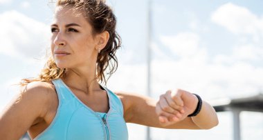 Kalp atışları için akıllı bir saat. Sportif bir yaşam tarzı, koç ara verir. Şehir seti işleten kendine güvenen bir kadın, sporcu figürü, rahat spor kıyafetleri..