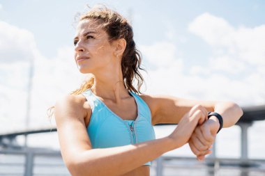 Fitness ve sağlıklı bir yaşam tarzı. Koç egzersizler arasında mola verir. Ellerdeki nabzı ölçmek için akıllı bir saat kullanıyor. Sokakta spor yapan bir kadın..