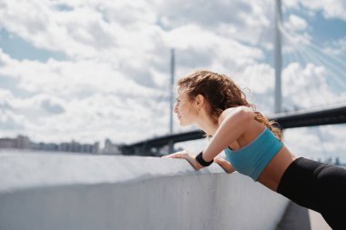 Şehirde fitness kardiyo çalışması var. Bir kadın ısınıyor ve egzersiz yapıyor. Sağlık ve yaşam tarzı, özgüven. Koç uzaktan bir maratona hazırlanıyor..