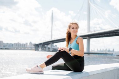 İnce vücutlu ve rahat giysiler. Sağlıklı yaşam tarzı kavramı. Güçlü bir esmer kadın fitness eğitmeni dışarıda güç egzersizleri yapar..