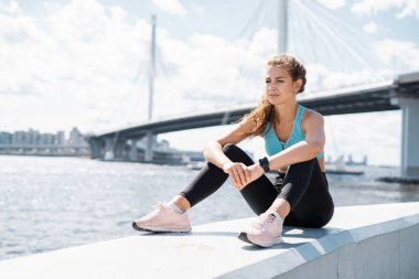 Dinlenmek için bir mola. Kadın bir koç sokakta spor yapıyor. Elimde akıllı bir saat var. Sporcu en sevdiği sağlık egzersizlerini yapar..