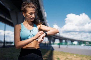 Sportif bir kadın açık havada egzersiz yapar. Antrenör sokakta fitness yapıyor. Kalorileri saymak için akıllı bir saat. Sağlıklı yaşam tarzı, şehirdeki spor aktiviteleri..