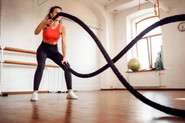 Bir aerobik koçu egzersiz yapar. Antrenman için rahat dar giysiler. Spor malzemesi kullanıyor. İnce beden kardiyo dersleri. Sportif bir kadın ve sağlıklı bir yaşam tarzı..