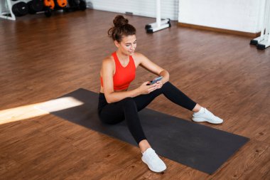 Telefonunu kullanıyor. Kendine güvenen bir kadın kulüpte spor yapar. Sağlıklı yaşam tarzı ve dayanıklılık eğitimi. Antrenör ve spor salonunda çalış..