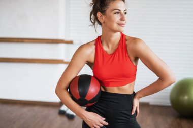 Kendine güvenen bir kadın spor için içeri giriyor, atletik bir vücudu var, elinde bir top tutuyor. Sağlıklı yaşam tarzı ve egzersiz. Spor salonunda antrenör..