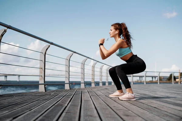 Güçlü bir esmer kadın fitness eğitmeni dışarıda güç egzersizi yapar. Sağlıklı yaşam tarzı kavramı. İnce beden ve rahat ayakkabılar..