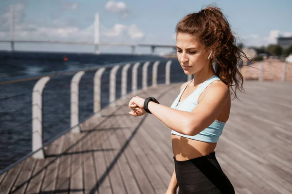 Egzersiz yapan ve koşan bir kadının portresi. Akıllı saat kalp atış hızı ölçümü. Antrenör bir mesafe maratonudur. Şehirde fitness kardiyo çalışması var. Sağlık ve yaşam tarzı.