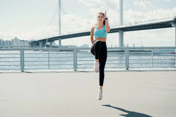 锻炼伸展肌肉以锻炼身体是很活跃的 燃烧体内的热量 这位运动员是个跑步者 他过着健康的生活 一个女人在城里的大街上训练田径运动员 — 图库照片