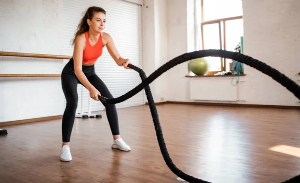 Trainer at the fitness club. A confident woman does cardio, an athletic body, holds sports equipment in her hands. Healthy lifestyle and exercise.