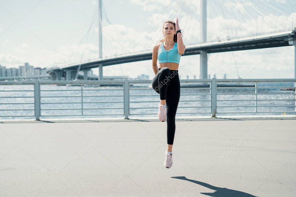 Exercises stretching muscles for fitness are active. Burns calories in the body. The athlete is a runner who leads a healthy lifestyle. Athletic figure a woman trains on the street in the city.