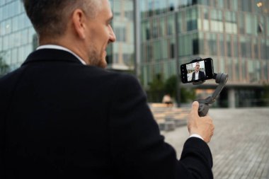 Müdür blogu için bir video kaydediyor. Ekonomist telefondaki bir uygulama aracılığıyla video iletişimi ile iletişim kurar. Resim stabilizasyonu için özel bir aygıt.