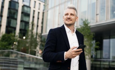 Avukat müşteriyle mesajlaşarak iletişim kurar. Bir iş adamı şık bir ceket giyer. Yönetici beyaz bir yetişkin, şık gri saçlı bir adam..