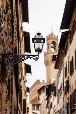 Floransa 'da duvardaki eski bir feneri bulutlu bir günde Palazzo Vecchio' nun arka planına yakın tut. Ortaçağ mimarisinin ayrıntıları