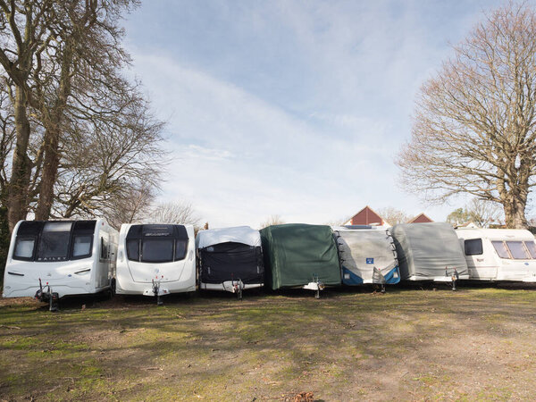 Можно увидеть человека, работающего с лестницы, чтобы снять пластиковые трубы с крыши автомобиля, находящегося в рекреационном центре.