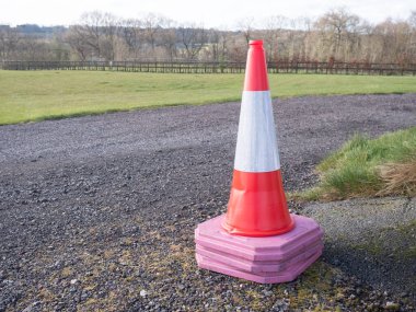 Pembe tabanlı bir yığın trafik konisi arka planda çimenli ve kırsal alanda asfalt üzerinde duruyor. Sağlık ve Güvenlik