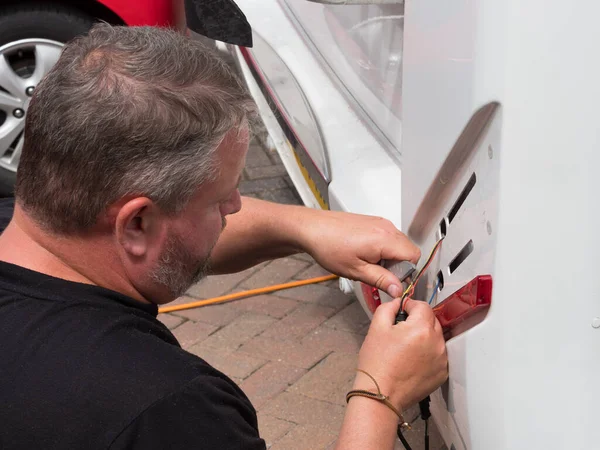 Bir elektrikçi, bir karavan eğlence aracındaki gösterge üzerinde çalışmak için bıçak kullanır. Gösterge yuvası kaldırıldı