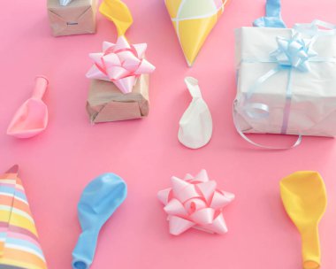 Pembe bir arka planda doğum günü süslemeleri. Balonlar ve hediyeler.