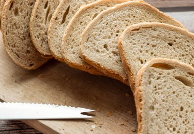 Dilimlenmiş taze ekmek ve kırsal bir masada bir bıçak. Yakınlarda un ve yumurta var.