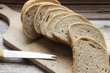 Dilimlenmiş taze ekmek ve kırsal bir masada bir bıçak. Yakınlarda un ve yumurta var.