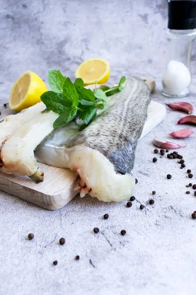 Fresh fish, raw cod fillet. Lies on a wooden board in the kitchen