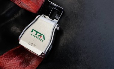 Roma, IT, Ekim 2021: Metalin üzerinde ITA Airways logosu yazılı bir uçağın içindeki boş bir koltuğun kırmızı kemeri. ITA Airways, 15 Ekim 2021 'den itibaren yeni İtalyan bayrak taşıyıcısı.