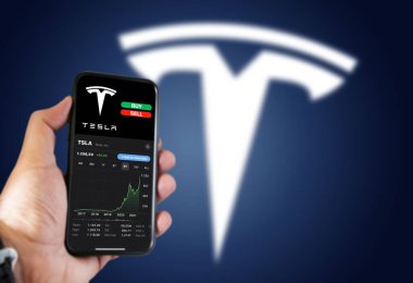 New York, ABD, Kasım 2021: Tesla Motors hisse senedi tablosu ile bir telefon tutmak ve ekranda düğme alıp satmak. Finansal yatırım ve iş. Borsa ve para.