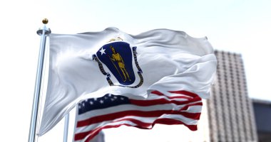Amerika Birleşik Devletleri 'nin Massachusetts eyaletinin bayrağı rüzgarda sallanıyor ve arka planda Amerikan bayrağı bulanıklaşıyor. Massachusetts 6 Şubat 1788 'de 6.