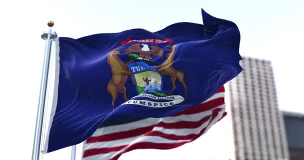 アメリカのミシガン州の旗が風になびいてアメリカの旗が背景にぼやけていました ミシガンは1837年1月26日に合衆国第26番目の州として加盟した — ストック動画