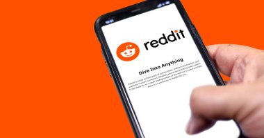 Roma, İtalya, Ocak 2022: Elinde turuncu arka planda Reddit mobil uygulaması olan akıllı bir telefon var. Reddit bir Amerikan sosyal haber toplama ve tartışma web sitesi başvurusudur.