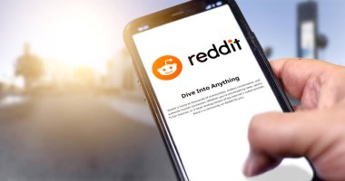 Roma, İtalya, Ocak 2022: Şehir planında Reddit mobil uygulaması olan akıllı bir telefonu ekranda tutmak. Reddit bir Amerikan sosyal haber toplama ve tartışma web sitesi başvurusudur.