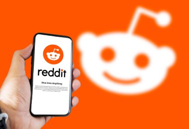 San Francisco, ABD, Aralık 2021: Ekranda Reddit mobil uygulaması olan bir telefon. Snoo Reddit uzaylısı turuncu arka planda bulanıklaştı. Sosyal haber toplama ve tartışma web sitesi
