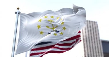the flag of the US state of Rhode Island waving in the wind with the American flag blurred in the background. Rhode Island was admitted to the Union on May 29, 1790 as 13th state
