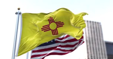 ABD 'nin New Mexico eyaletinin bayrağı rüzgarda dalgalanırken arka planda Amerikan bayrağı bulanıklaştı. New Mexico eyalet bayrağı mavi renk içermeyen dört Amerikan bayrağından biridir.